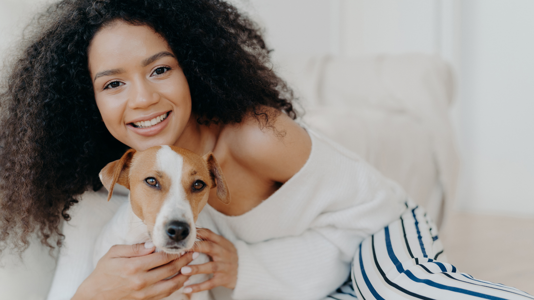 Woman smiling and holding her dog indoors, showcasing pet accessories